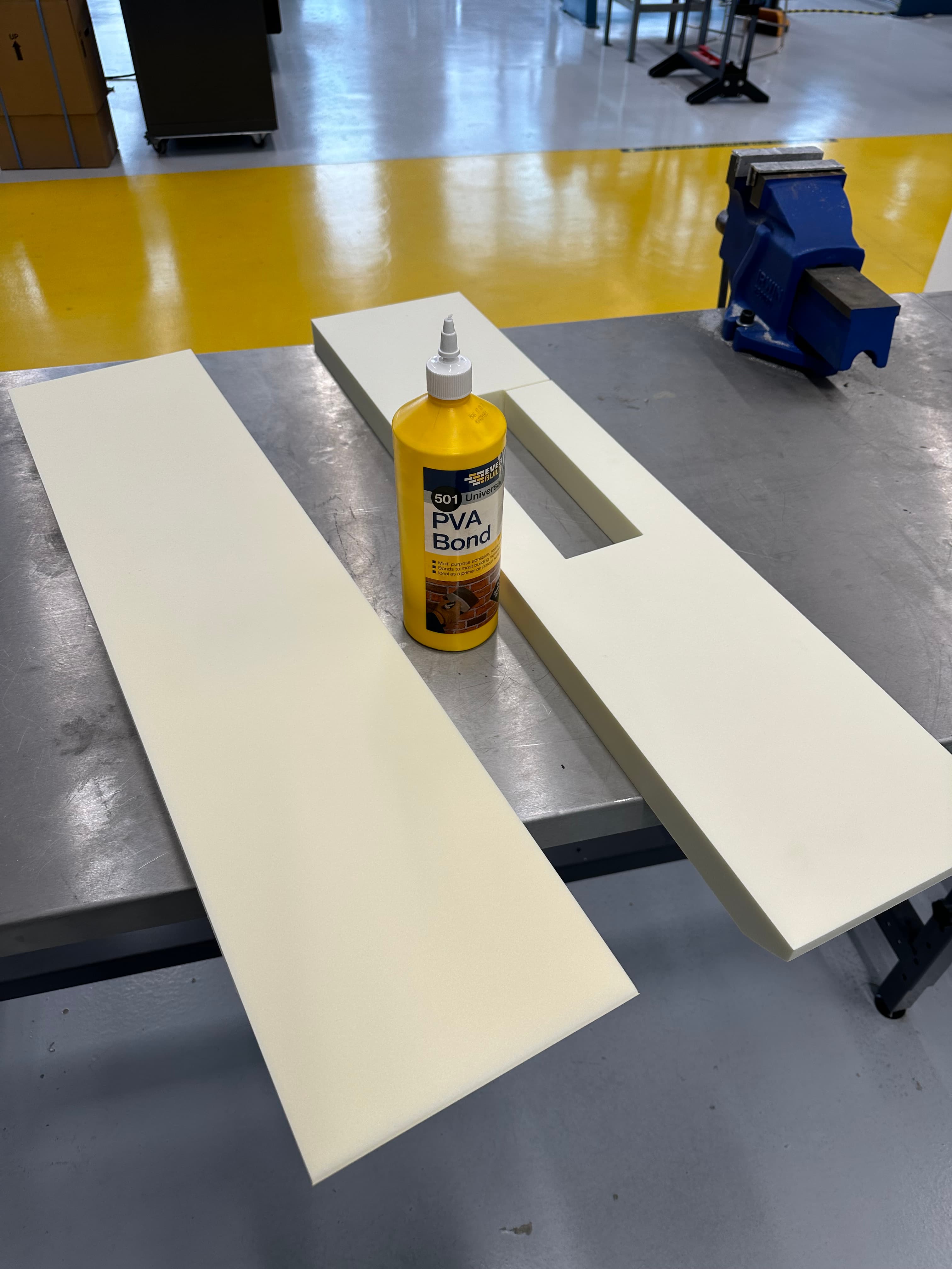 Partially constructed unmanned surface vehicle hull placed on a workbench in a workshop environment, surrounded by tools and materials, evoking a sense of progress and hands-on engineering
